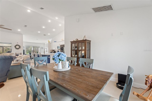 dining space with light tile patterned floors, high vaulted ceiling, and sink