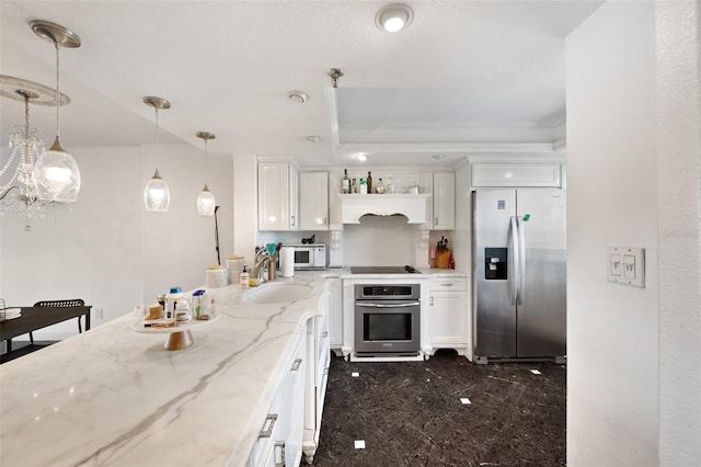 kitchen with sink, hanging light fixtures, appliances with stainless steel finishes, light stone countertops, and white cabinets