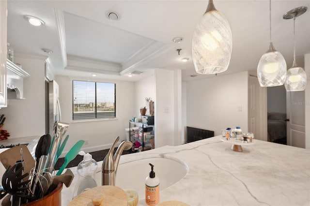 kitchen with crown molding, sink, light stone counters, and a tray ceiling