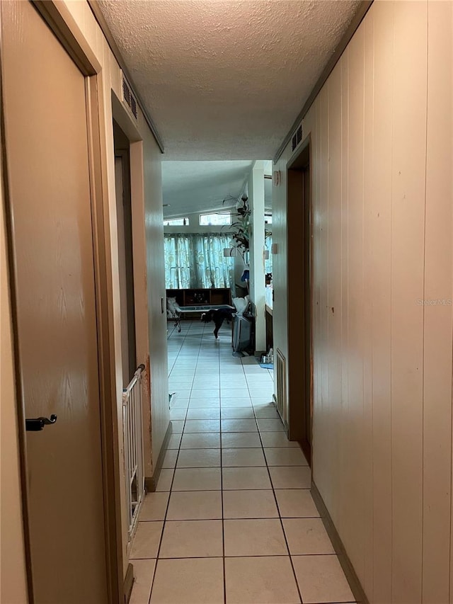 hall with a textured ceiling and light tile patterned flooring