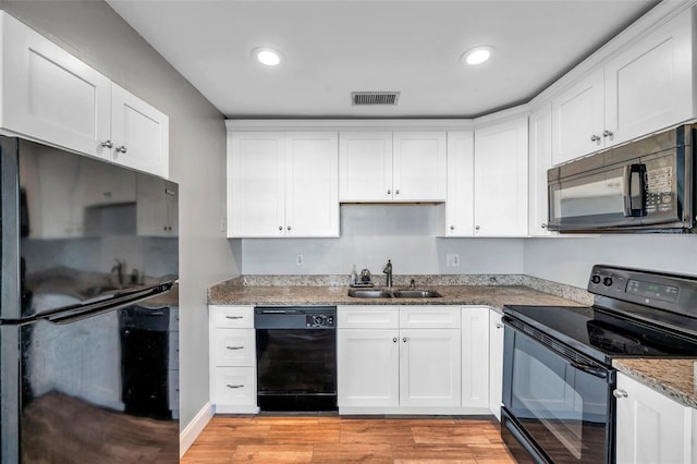 kitchen with white cabinetry, sink, black appliances, and light wood-type flooring