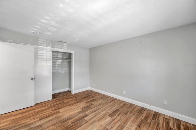 unfurnished bedroom with a closet, a textured ceiling, and light hardwood / wood-style flooring