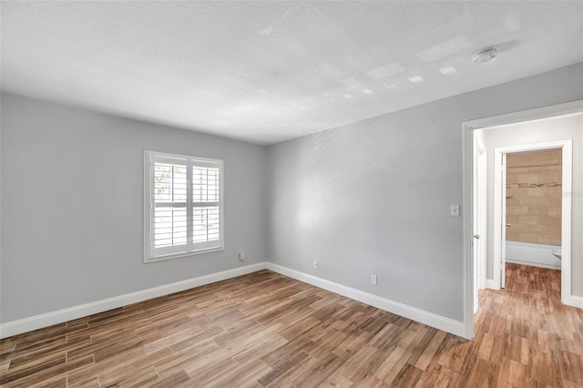 unfurnished room with a textured ceiling and light hardwood / wood-style flooring