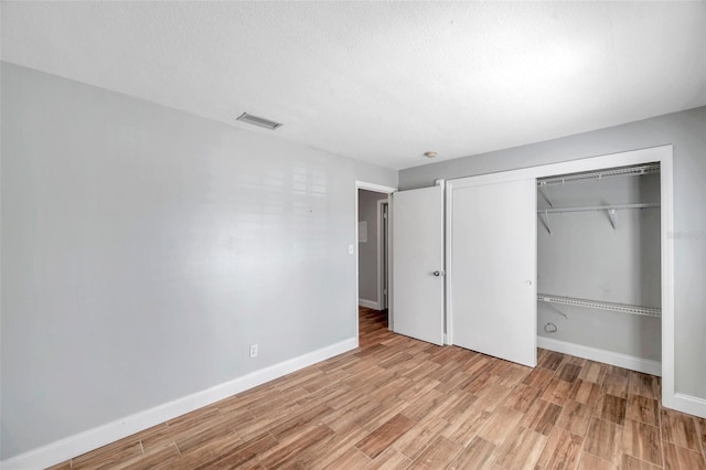 unfurnished bedroom featuring light hardwood / wood-style floors, a closet, and a textured ceiling