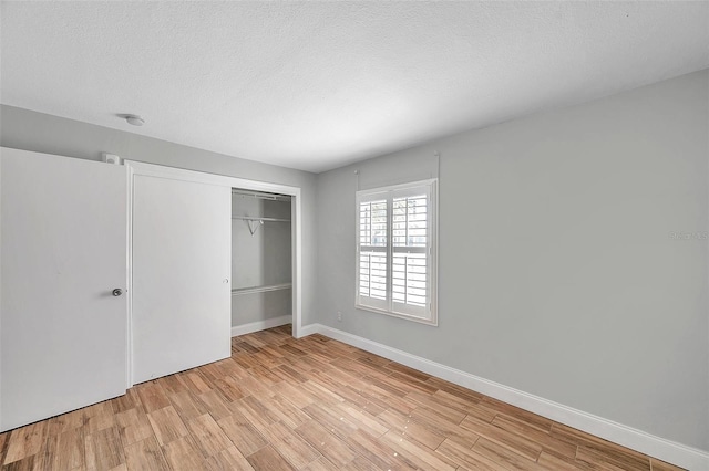 unfurnished bedroom featuring a textured ceiling, light wood-type flooring, and a closet