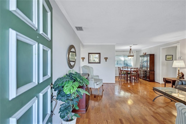 living room with hardwood / wood-style floors, ornamental molding, and a textured ceiling