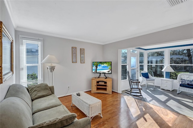 living room featuring crown molding, light hardwood / wood-style floors, and a wealth of natural light