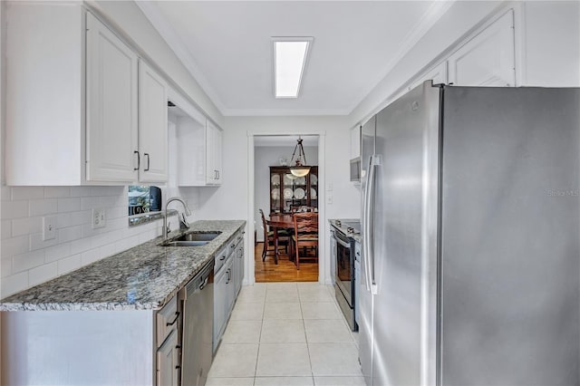 kitchen with sink, light tile patterned floors, stainless steel appliances, decorative backsplash, and white cabinets