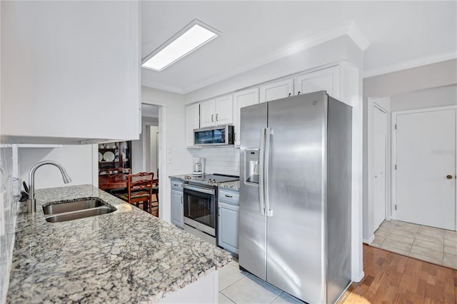 kitchen with sink, white cabinets, ornamental molding, light stone counters, and stainless steel appliances