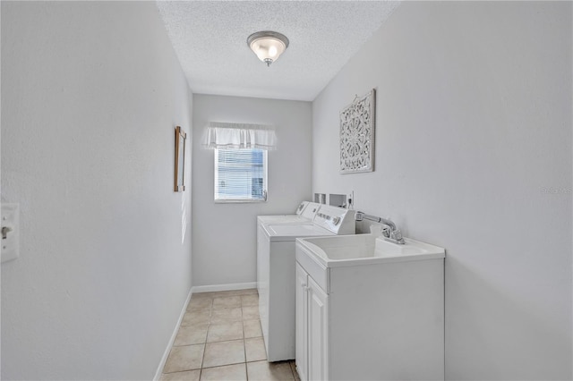 laundry area featuring sink, washer and dryer, light tile patterned floors, and a textured ceiling