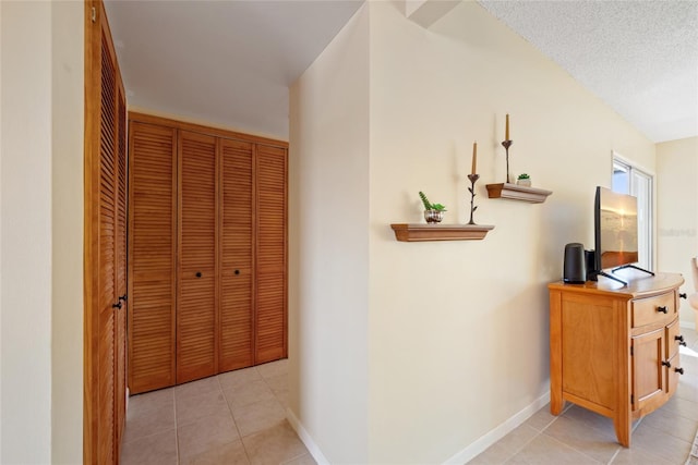 hallway with light tile patterned flooring and a textured ceiling