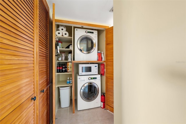 laundry room featuring stacked washer and dryer and light tile patterned flooring