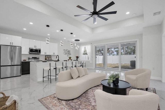 living room featuring a tray ceiling and ceiling fan