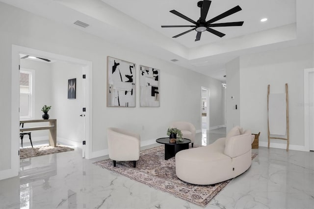 sitting room featuring a raised ceiling and ceiling fan