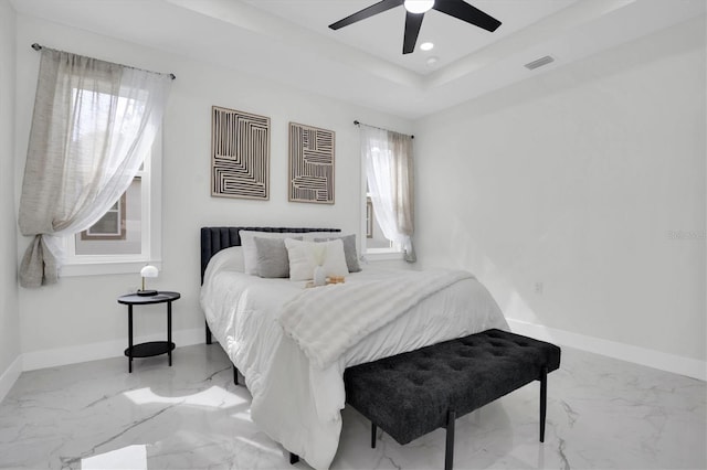 bedroom featuring ceiling fan, a tray ceiling, and multiple windows