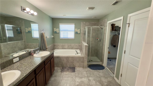 bathroom featuring vanity, plus walk in shower, tile patterned flooring, and a textured ceiling