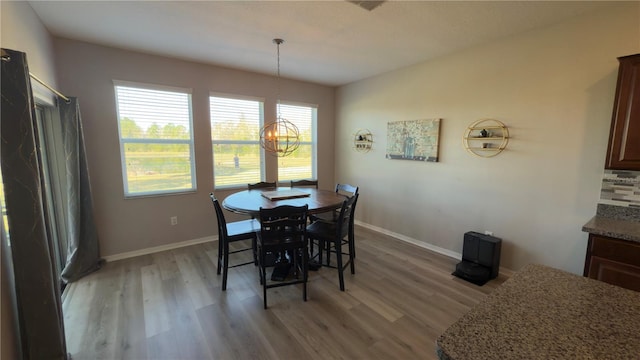 dining space with light hardwood / wood-style floors and a chandelier