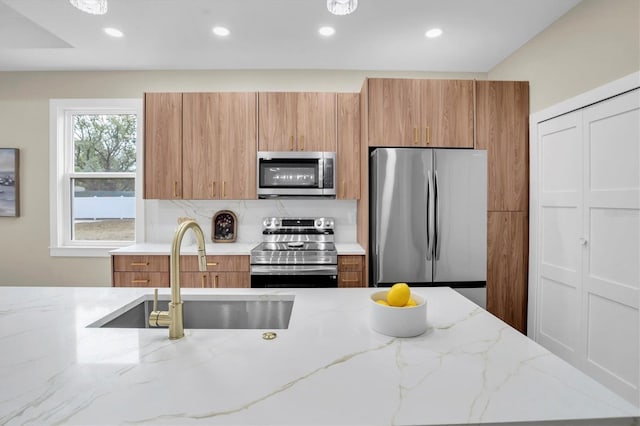 kitchen featuring light stone countertops, appliances with stainless steel finishes, sink, and decorative backsplash