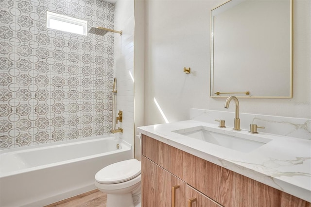 full bathroom featuring tiled shower / bath, hardwood / wood-style floors, vanity, and toilet