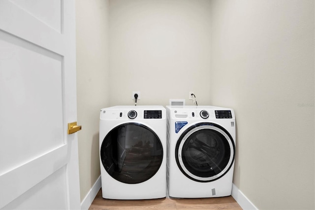 laundry area featuring separate washer and dryer and light hardwood / wood-style floors