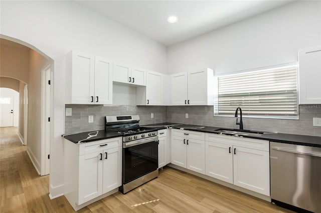 kitchen featuring white cabinetry, sink, backsplash, stainless steel appliances, and light wood-type flooring