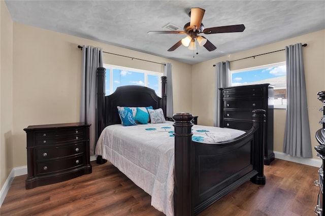 bedroom featuring dark hardwood / wood-style flooring, multiple windows, and ceiling fan