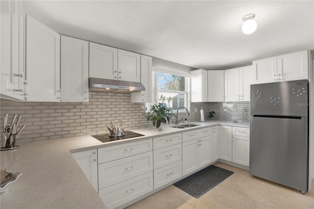 kitchen with white cabinetry, sink, stainless steel fridge, and black electric stovetop
