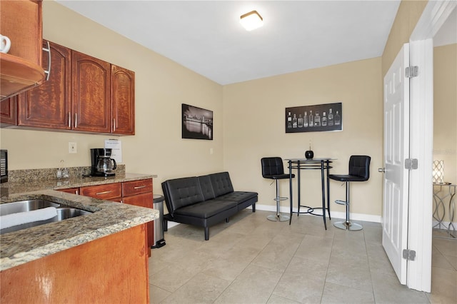 kitchen with light tile patterned floors, light stone countertops, and sink