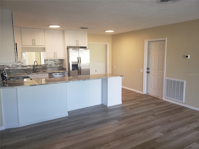 kitchen featuring tasteful backsplash, white cabinetry, sink, stainless steel appliances, and dark wood-type flooring