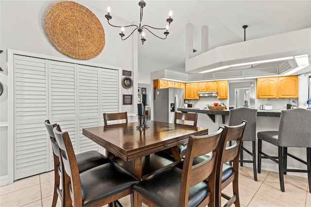 dining room featuring a towering ceiling, a chandelier, and light tile patterned floors