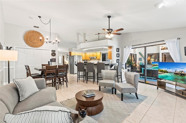 living room featuring ceiling fan with notable chandelier, vaulted ceiling, and light tile patterned floors