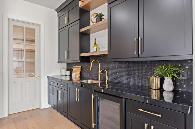 bar featuring wine cooler, indoor wet bar, light wood-style flooring, backsplash, and a sink