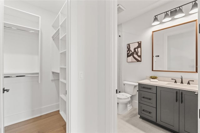 full bathroom with visible vents, toilet, vanity, wood finished floors, and baseboards