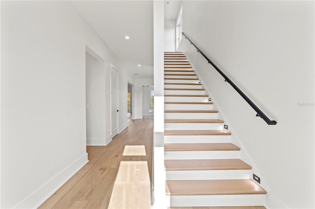 staircase with baseboards, wood finished floors, and recessed lighting