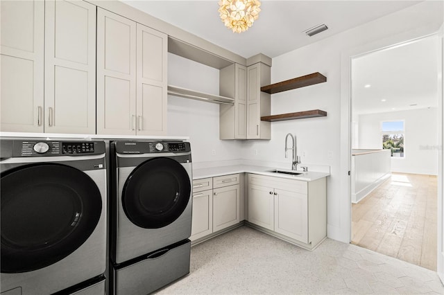 laundry area with washer and dryer, cabinet space, a sink, and visible vents