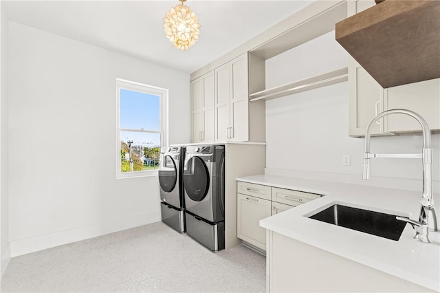 clothes washing area with cabinet space, a sink, washer and clothes dryer, and baseboards