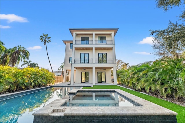 back of house featuring a patio area, fence, ceiling fan, a balcony, and an in ground hot tub