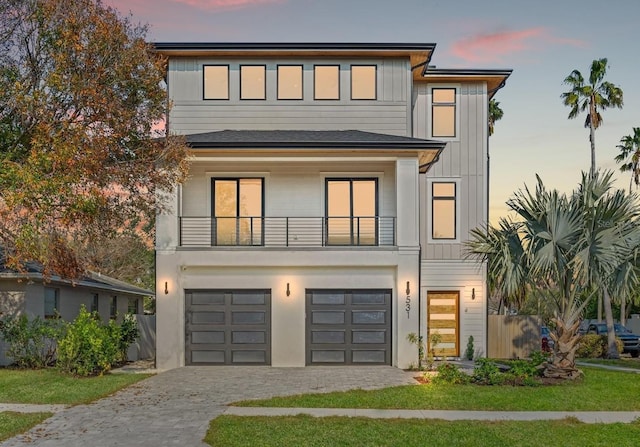 view of front of home with board and batten siding, decorative driveway, a balcony, and an attached garage