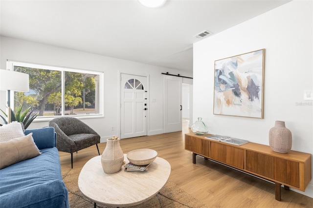 living room with a barn door and light hardwood / wood-style floors