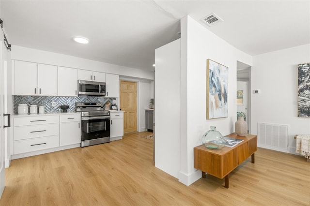 kitchen featuring backsplash, stainless steel appliances, light hardwood / wood-style floors, and white cabinets