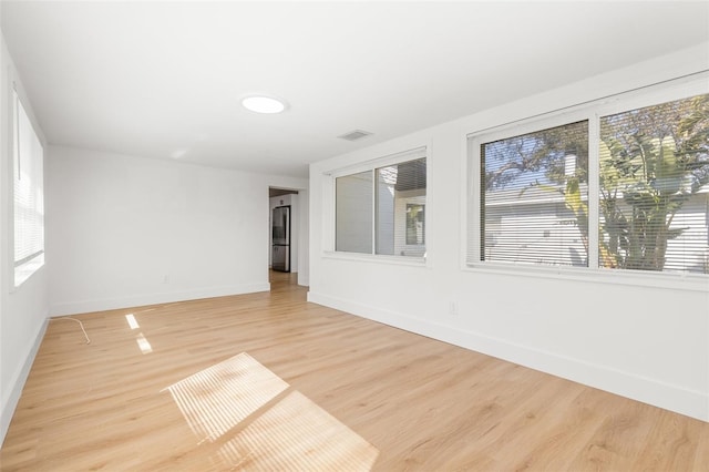 spare room with plenty of natural light and light hardwood / wood-style flooring