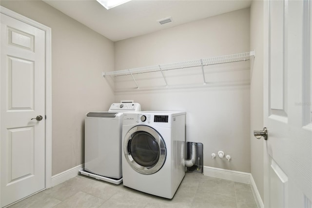 clothes washing area with light tile patterned floors and washing machine and clothes dryer