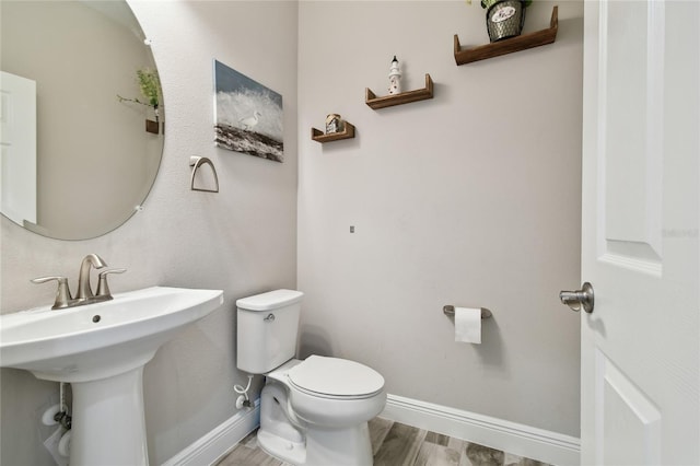 bathroom featuring wood-type flooring, toilet, and sink