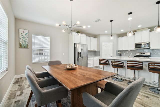 dining space featuring sink, a chandelier, and light wood-type flooring