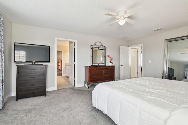 bedroom with light colored carpet, ceiling fan, and ensuite bathroom