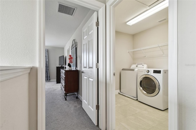 laundry area featuring light carpet and washer and clothes dryer