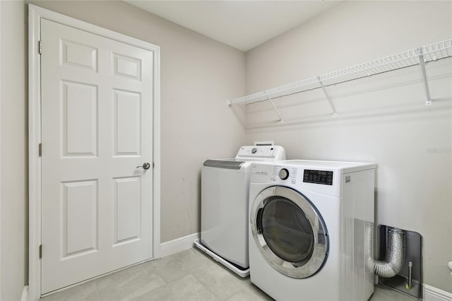 laundry room with washer and clothes dryer and light tile patterned floors