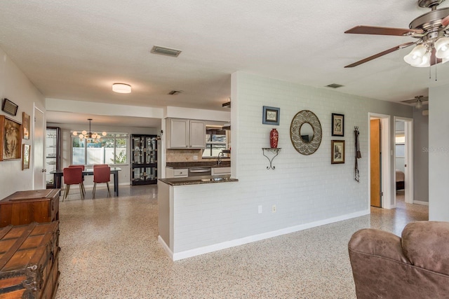 kitchen with sink, decorative light fixtures, a textured ceiling, stainless steel dishwasher, and kitchen peninsula