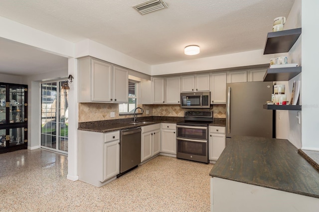 kitchen with appliances with stainless steel finishes, sink, decorative backsplash, and a textured ceiling