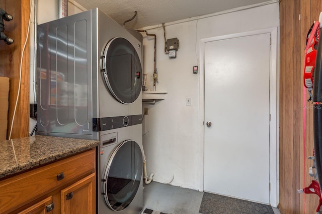 laundry room with cabinets and stacked washer / dryer